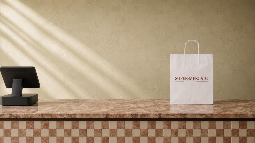 A Super Mercato paper bag waiting beside the till on the marble and mosaic counter